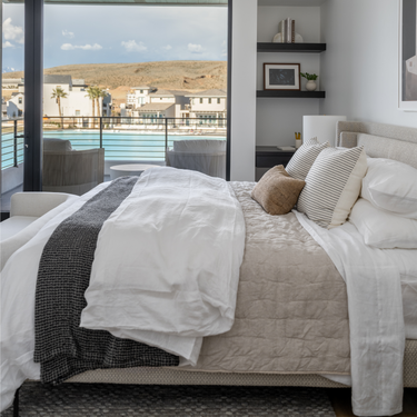 Modern bedroom with a view of a pool and ocean.